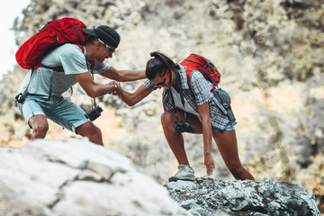 A couple with a backpack on their back hiking, surrounded by majestic mountains, planning the next...