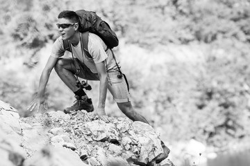A hiker with a backpack on his back hiking, surrounded by majestic mountains, planning the next steps of his adventurous journey.