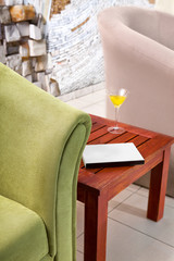 Detail of green armchair with table, book and coctail