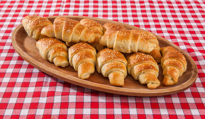 Croissant bakery on teakwood table on red and white fiber backgr