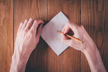 Man hand writing notes on napkin