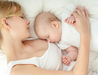Young mother and her baby, sleeping in bed. Mother and baby. Hap