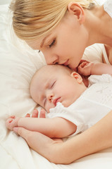 Young mother and her baby, sleeping in bed. Mother and baby. Hap