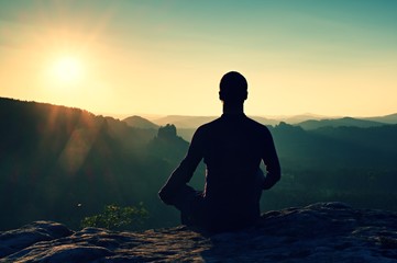 Hiker in squatting position on a rock, enjoy dybreak  scenery