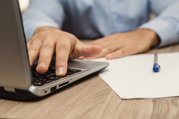 uomo in ufficio che per lavoro digita un pulsante dalla tastiera del notebook con il dito