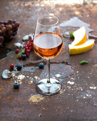 Glass of rose wine with berries, melon, grapes and ice on grunge