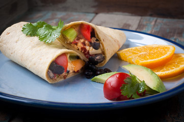 Delicious breakfast burrito stuffed with eggs, avocado, olives and chilli peppers. Served with tomato and salad and a slice of freshly cut orange.