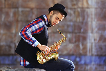 Man with saxophone outside near the brick wall