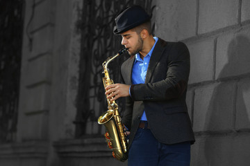 Fototapeta na wymiar Man with saxophone outside near the brick wall