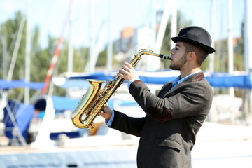 Young man playing on saxophone on the riverside
