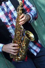 Handsome man plays saxophone on green wooden background, close up
