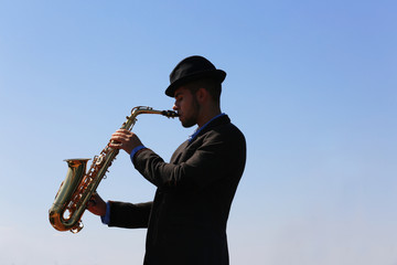 Obraz na płótnie Canvas Saxophonist plays on the pier