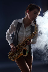 Fototapeta na wymiar Attractive woman plays saxophone on dark blue background