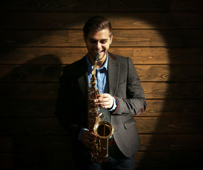 Elegant saxophonist plays jazz on wooden background