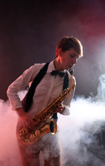 Obraz na płótnie Canvas Talent woman professionally plays saxophone in red smoke