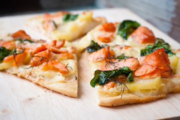 Home made white pizza topped with salmon, cheese and wilted spinach.