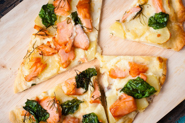 Home made white pizza topped with salmon, cheese and wilted spinach.