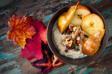 Healthy autumn, fall breakfast porridge of buckwheat groats topped with fresh sliced pear, walnuts, goji berries and pumpkin seeds. - obrazy, fototapety, plakaty