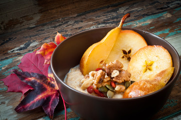 Healthy autumn, fall breakfast porridge of buckwheat groats topped with fresh sliced pear, walnuts, goji berries and pumpkin seeds.