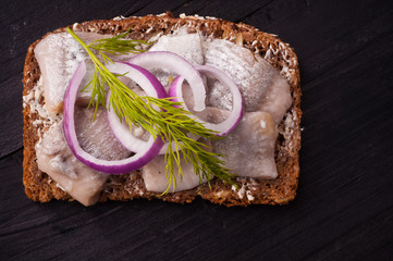 Traditional Scandinavian open sandwich of dark rye bread topped with cured herring, red onion and dill.
