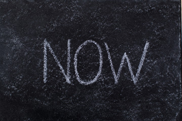 Fototapeta premium NOW written on blackboard