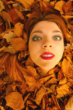 Portrait of young woman in autumn leaves.