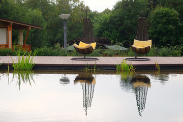 The image of chaise-longues around the pond outside
