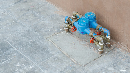 Blue water meter crose cover near the wall