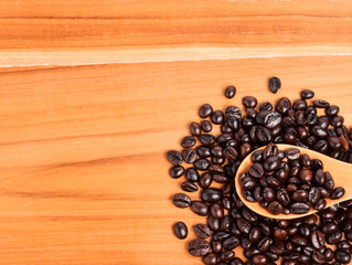 Coffee beans in wooden spoon on wooden background