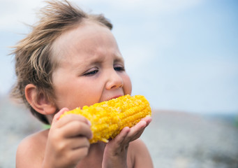 Boy eating corn on the beach