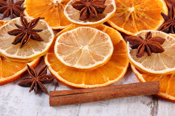 Slices of dried lemon, orange and spices on old wooden background