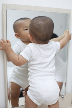 Chinese baby boy playing in front of a mirror