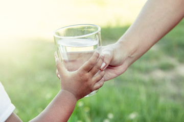 Woman hand giving glass of fresh water to child in the park © pingpao