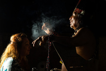 An ancient Mayan shaman woman conducting an ayahuasca ceremony in Ecuador, using plants for cultural healing and treatment of the sick, smoking a pipe.