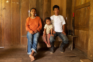 An Ecuadorian farmer and his family in the Amazon rainforest, cultivating cocoa to support their...