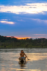 An indigenous adult man from Ecuador fishes in the protected Putumayo area of the Amazon, surrounded by lush greenery and serene waters.