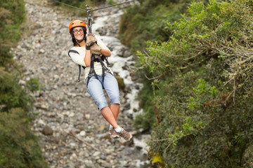 Obraz premium A woman ziplining through the lush jungle canopy of Ecuador, feeling the rush of adrenaline as she flies over a roaring river.
