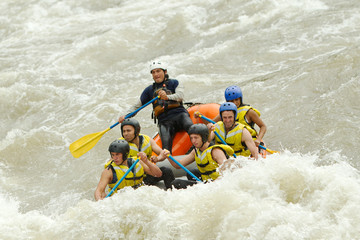 A group of friends navigating the white waters of a river in Ecuador, working together as a team while rafting.