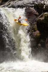 A thrilling image of a kayak jumping over rapids at Sangay waterfall in Ecuador, surrounded by white water and filled with extreme action and fun.