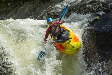 A thrilling white water adventure in Ecuador's extreme rapids, navigating through a waterfall, with kayaks and rafts on the rushing river.