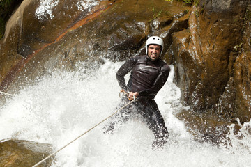 A climber descending a waterfall while canyoning in a dark, underground river during an exciting spelunking adventure.