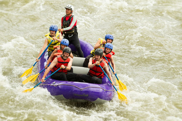 A team of adventurers in a raft navigating the rushing river, working together to conquer the rapids and embrace the thrill of water sports.