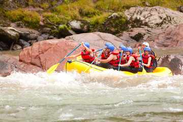 A diverse ensemble of tourist males and females led by a skilled instructor navigating through thrilling whitewater rapids on a river expedition in Ecuador