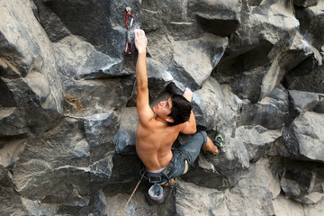 A male climber scaling a steep rock face, navigating dangerous terrain with skill and determination, feeling free in his element.