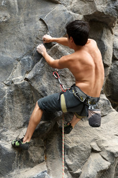 Experienced rock climber showcasing impressive strength and skill while gripping onto a minuscule crevice in the rock.