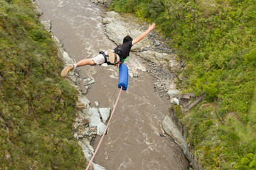 A person bungee jumping off a bridge with a rope, soaring through the air above a stunning waterfall below.