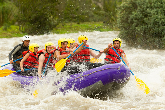 A team of men in Ecuador, surrounded by the wild white waters of a river, showcasing their teamwork and spirit of adventure in rafting competition.