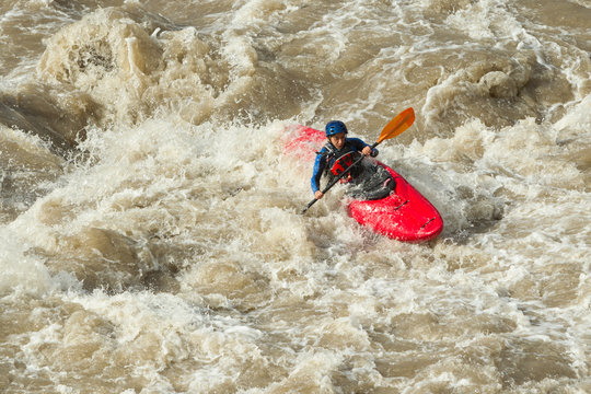 A group of adventurers navigating through the rapids in a kayak, approaching a breathtaking waterfall on a wild river.