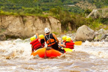 A diverse group of male and female sightseers being led by an experienced guide on an adventurous whitewater river rafting excursion in Ecuador