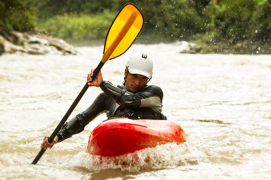 A group of men navigating through white water rapids in a dynamic and extreme sport, paddling their raft and kayak with cool precision.